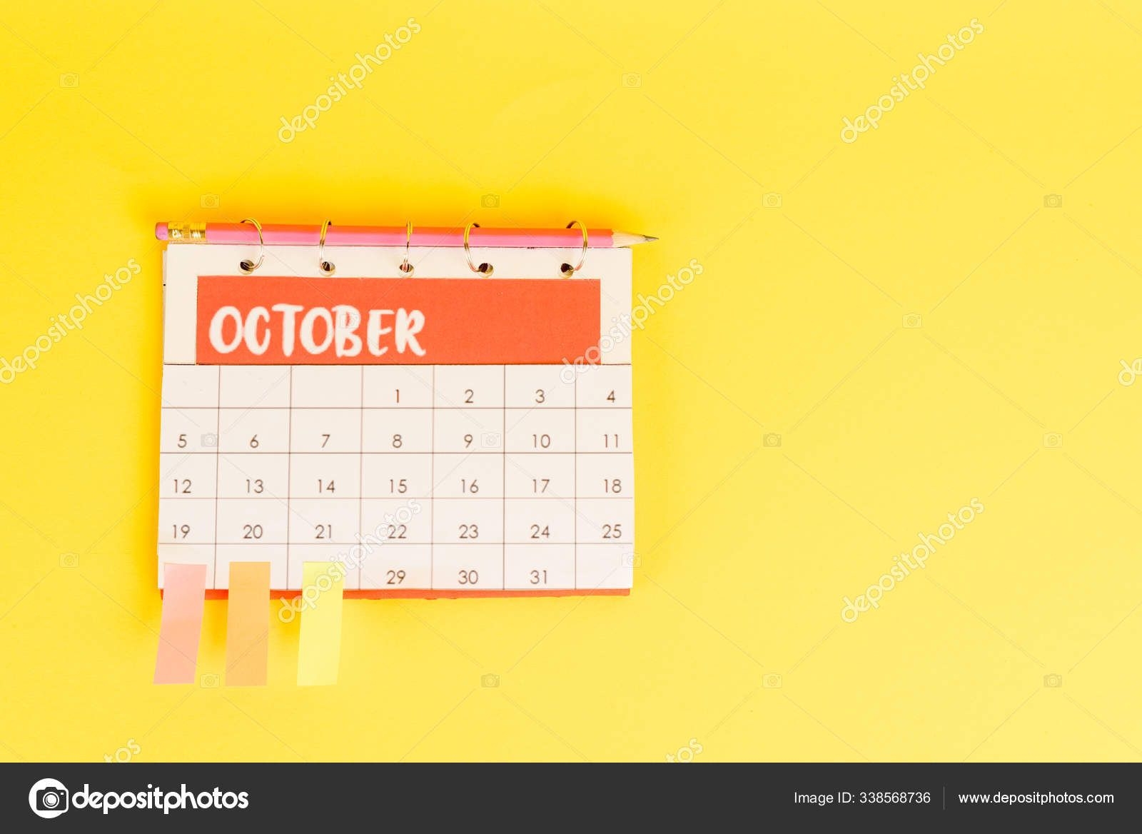 top view of pencil, calendar with october month and sticky notes on yellow background 338568736